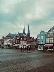 Delft, Netherlands - January 27,, 2021: Colorful street panoramic view with traditional dutch houses on the square, bicycles, people walking in downtown of popular Holland destination