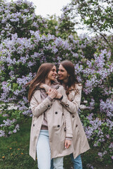 Twin sisters in the park with blooming trees