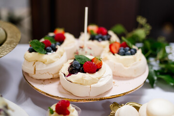Mini Pavlova meringue cake with fresh berries on a pink and golden plate