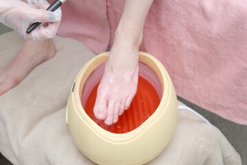woman foot treatment in paraffin bath at the spa.