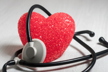The big red heart is wrapped in a stethoscope. The concept of medical care, and cardiology.
