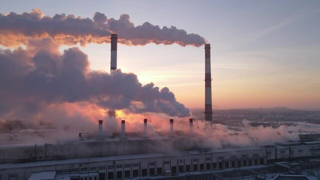 Smoke stacks over sunrise sky background. Energy generation and air environment pollution industrial scene.