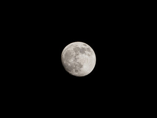  closeup of a nearly full moon with its craters in the black night sky