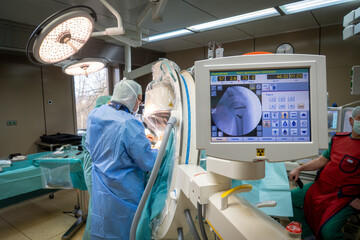 doctor is operating on a shoulder in an operating room and in the foreground is an x-ray machine