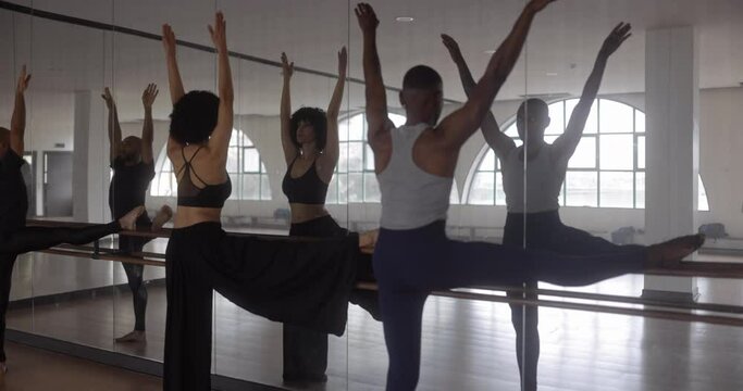 Teacher and students stretching leg on barre in dance studio