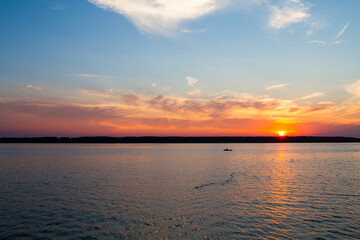 Sunset on the lake. A fisherman is fishing from a boat