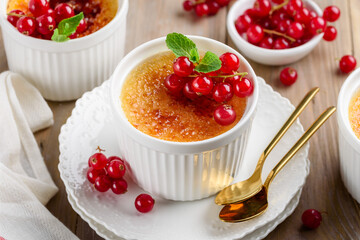 Creme brulee decorated with red currant and mint. Traditional french vanilla cream dessert with caramelised sugar. Selective focus