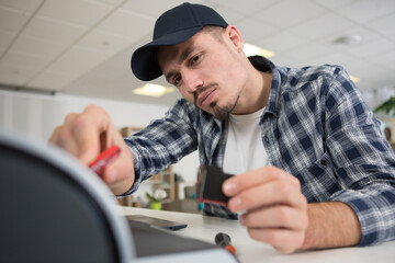 man repairing photocopier using screwdriver