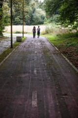 Obraz premium Two women walking along the bike path in a town in Galicia. In front they have a cornfield
