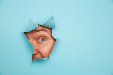 Man looking through torn background.