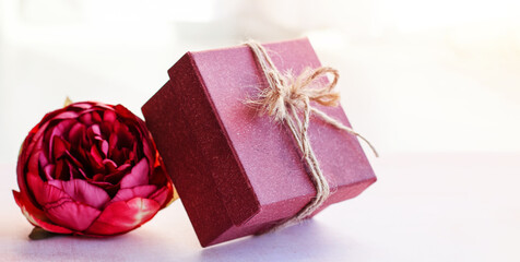 Gift vintage box together with a pink flower on the table on a light background. Natural light. Festive concept. Happy mother's day, women's day, valentine's day or birthday.