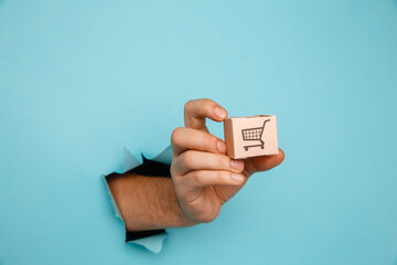 Hand with a delivery box through a blue paper hole.
