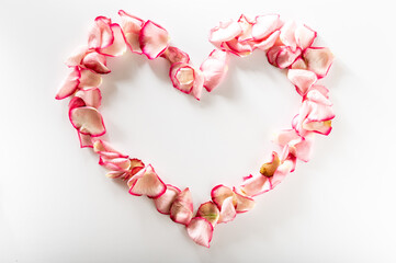 Obraz premium Heart shaped rose petals. Heart made of flowers on a white background. Lovers