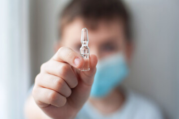 the boy is holding an ampoule of vaccine. Ampoule close-up
