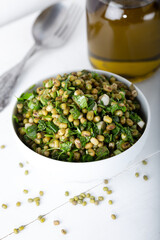 Mung bean salad with vegetables and olive oil on the white wooden background. 
