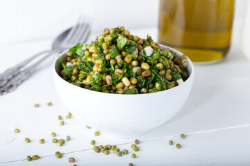 Mung bean salad with vegetables and olive oil on the white wooden background. 