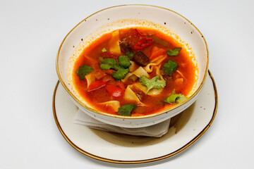 Spicy soup in a deep plate on a white background
