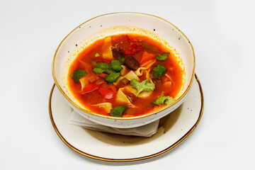Spicy soup in a deep plate on a white background