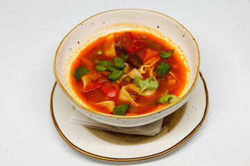 Spicy soup in a deep plate on a white background
