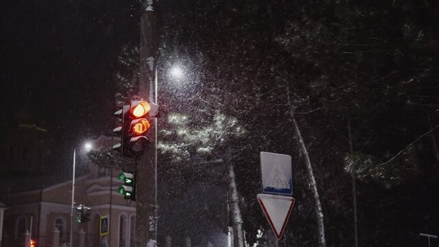 Traffic light in the city at the intersection in the winter night with snow