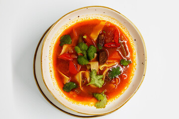 Spicy soup in a deep plate on a white background