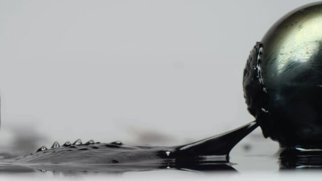 Black ferrofluid moves away from rock and jumps onto magnetic ball