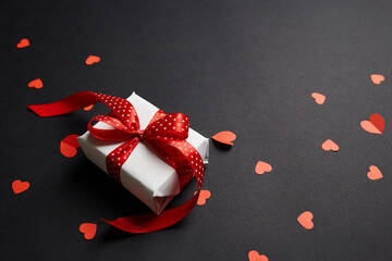 Valentines day gift box with red hearts on black paper background