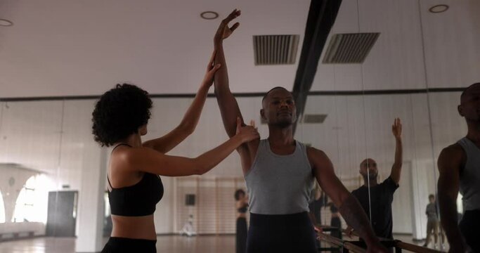 Coach adjusting male dancer arm pose in dance studio