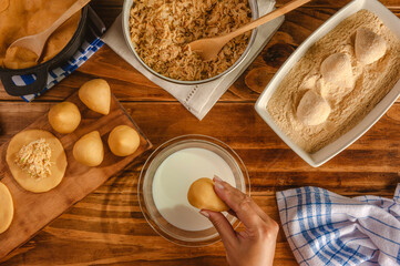 Hands of woman preparing brazilian croquette (coxinha de frango) on a wooden kitchen table