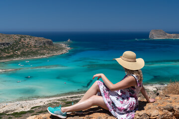 Panoramic view of Balos Lagoon, with magical turquoise waters, lagoons, tropical beaches of pure white, pink sand and Gramvousa island on Crete, Greece. Girl with blond curly hair and a cap posing