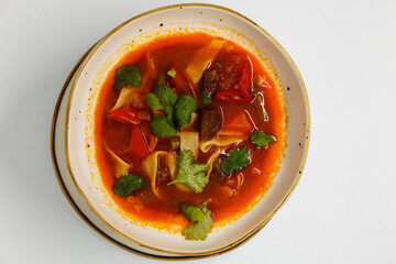 Spicy soup in a deep plate on a white background
