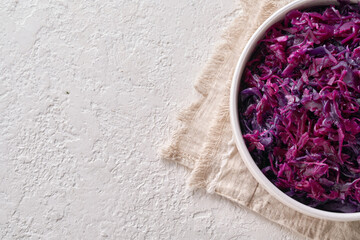 Obraz na płótnie Canvas Fermented purple cabbage in a white bowl on a bright background with copy space