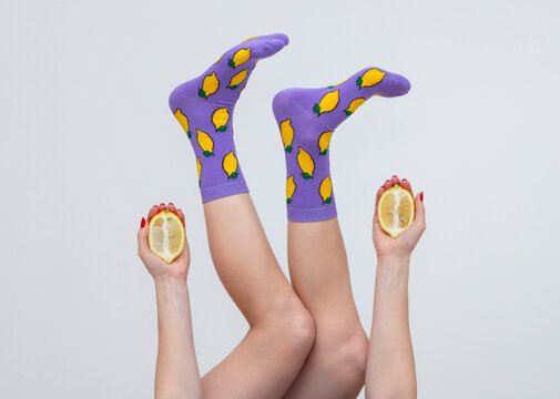 female legs in colorful socks with lemons isolated on white background