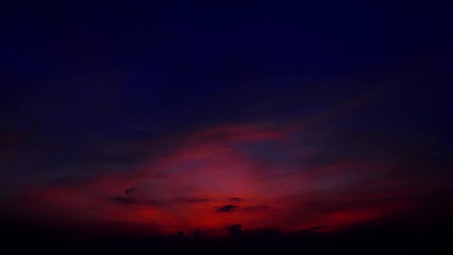 Rich red, yellow and blue colours and shades of sunset afterglow on high clouds. Light quickly fade down, evening to night time lapse shot. Tropical country nature, sunset view at sea shore