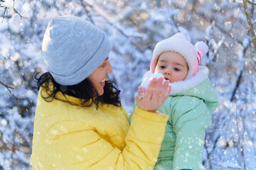 family portrait in the winter forest, mother and child looks on snow, bright sunlight and shadows on the snow, beautiful nature