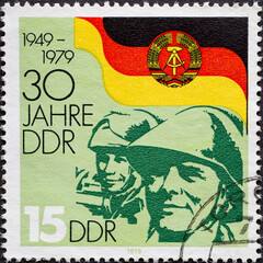 GERMANY, DDR - CIRCA 1979 : a postage stamp from Germany, GDR showing Faces of soldiers of the NVA in front of the flag of the GDR: 30 years of the GDR