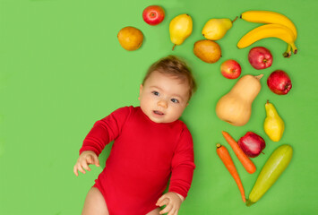 Fototapeta na wymiar Cute baby boy lies on green background and surrounded with fresh organic fruits and vegetables. First baby food.Top view. Healthy child nutrition, baby feeding.