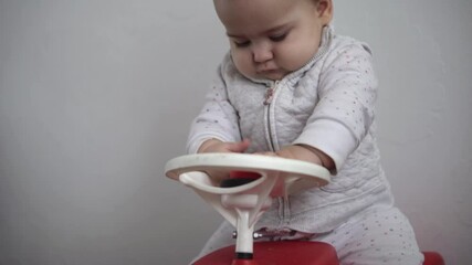 Childhood, entertainment, games, transport, motherhood concepts - active happy smiling joyful chubby infant baby kid child 10 months play ride big toy plastic red car scooter and beeps at home indoors