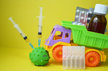 The toy is given an injection from the covid 19 coronavirus vaccine. A typewriter, medicines and syringes on a yellow background. Medical concept of vaccination and control of the covid-19 pandemic.
