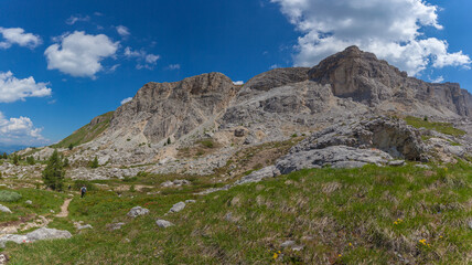 Panorama of Mount Settsass western side with unrecognizable man walking on a hiking trail, Dolomites, Italy