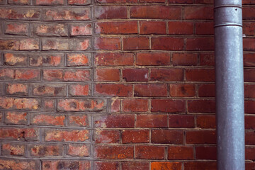 antique red brick wall with metallic water pipe - city background, place for text message and announcement