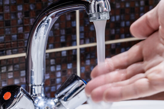 Faucet At Domestic Bathroom With Low Water Pressure. Person Check Water Temperature To Adjust It. Leaky Tap Repair