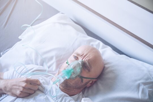 Sick Man With Breathing Problem With Oxygen Mask Or Ventilator On Hospital Bed