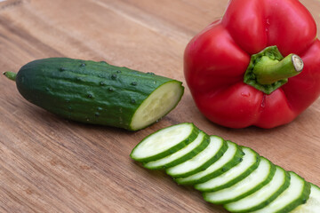 Sliced cucumber and red pepper on a wooden table