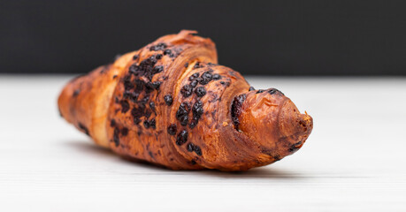 From above of delicious fresh crusty croissant and pieces of dark chocolate composed on a dark background.