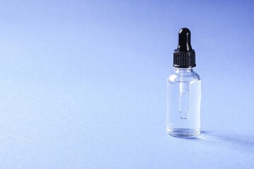 Skin care essence oil dropper in glass bottle on blue background