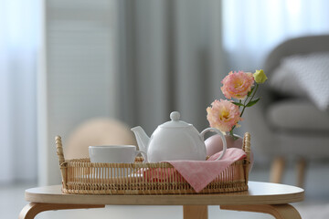 Fototapeta na wymiar Cup of hot drink, teapot and beautiful eustoma flowers on table indoors, space for text