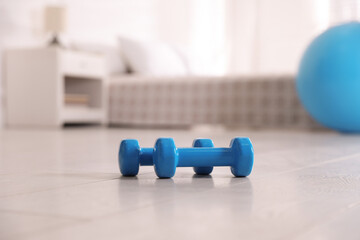 Blue dumbbells on floor in room. Home fitness