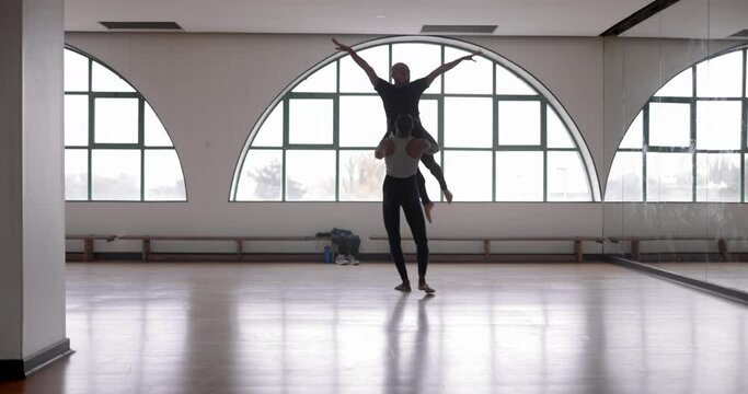 Male dancer lifting partner up while dancing in studio