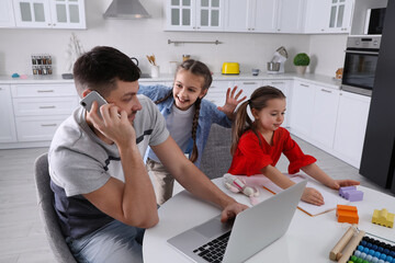 Children disturbing stressed man in kitchen. Working from home during quarantine